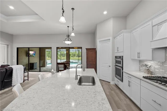 a large kitchen with kitchen island a large window a sink stainless steel appliances and cabinets