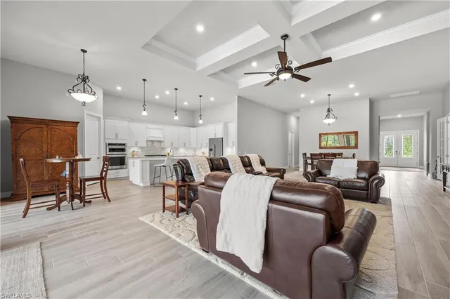 a living room with furniture kitchen view and a chandelier