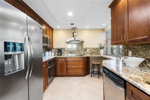 a kitchen with granite countertop a sink stainless steel appliances and cabinets