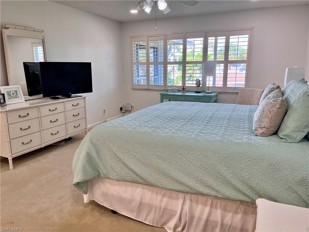 232 Memory Lane, Unit 4 Naples, FL 34112 - Photo 14 of 33 a spacious bedroom with a bed and a flat screen tv
