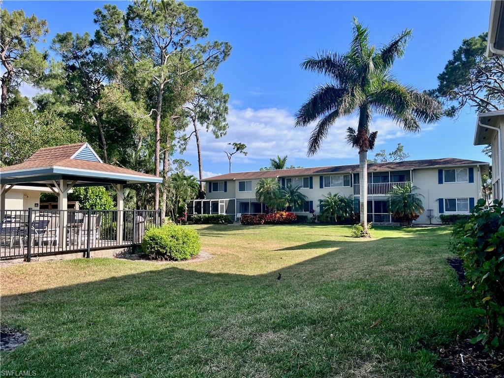 232 Memory Lane, Unit 4 Naples, FL 34112 - Photo 22 of 33 a view of a swimming pool with lawn chairs under an umbrella