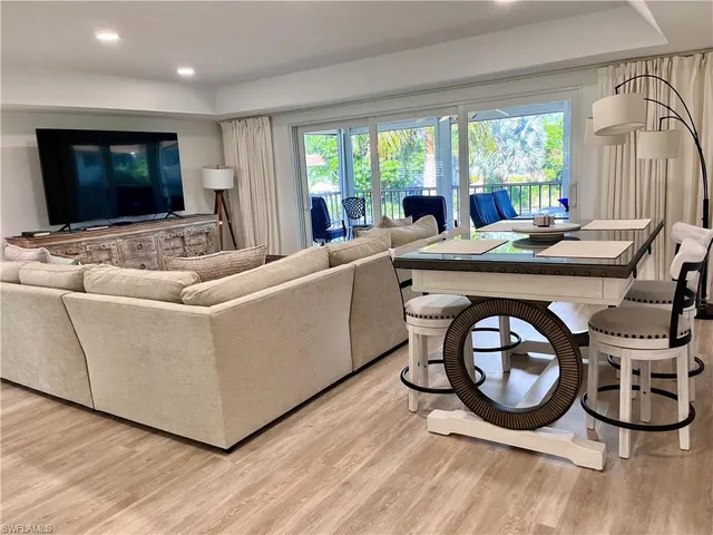 a living room with furniture a flat screen tv and a large window