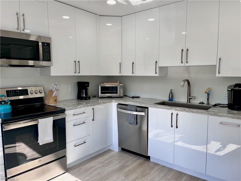 232 Memory Lane, Unit 4 Naples, FL 34112 - Photo 8 of 33 a kitchen with granite countertop white cabinets and black stainless steel appliances