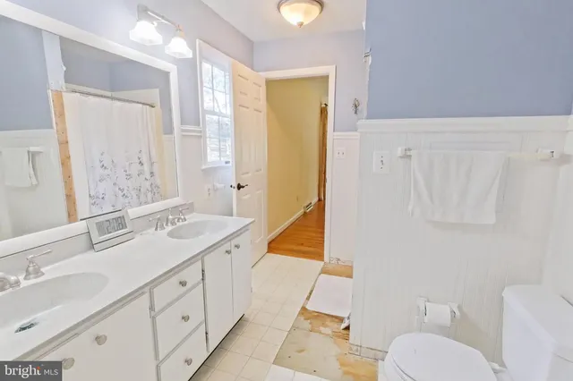 a spacious bathroom with 2 sink toilet and a mirror