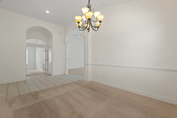 a view of an empty room with a chandelier fan