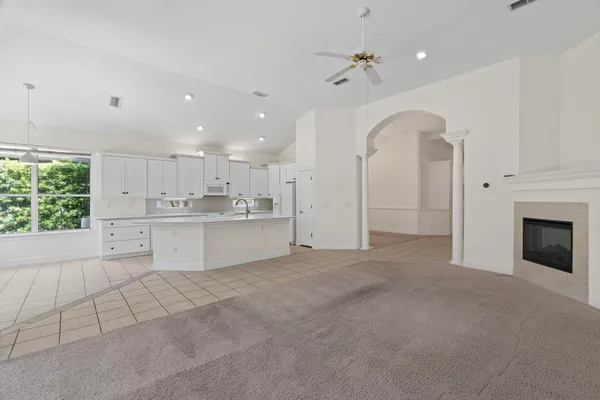 a large white kitchen with a fireplace and window