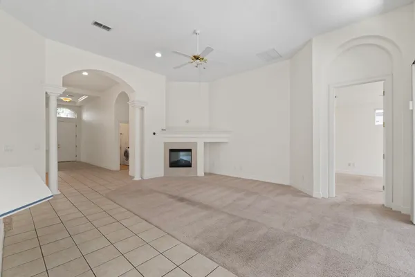 an empty room with fireplace and a chandelier fan
