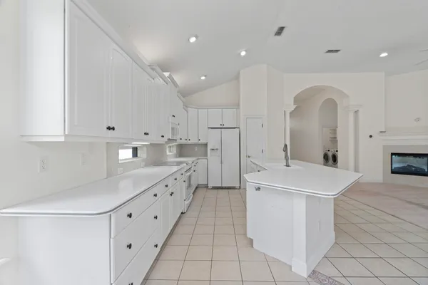 a large white kitchen with a sink and dishwasher a stove with wooden floors
