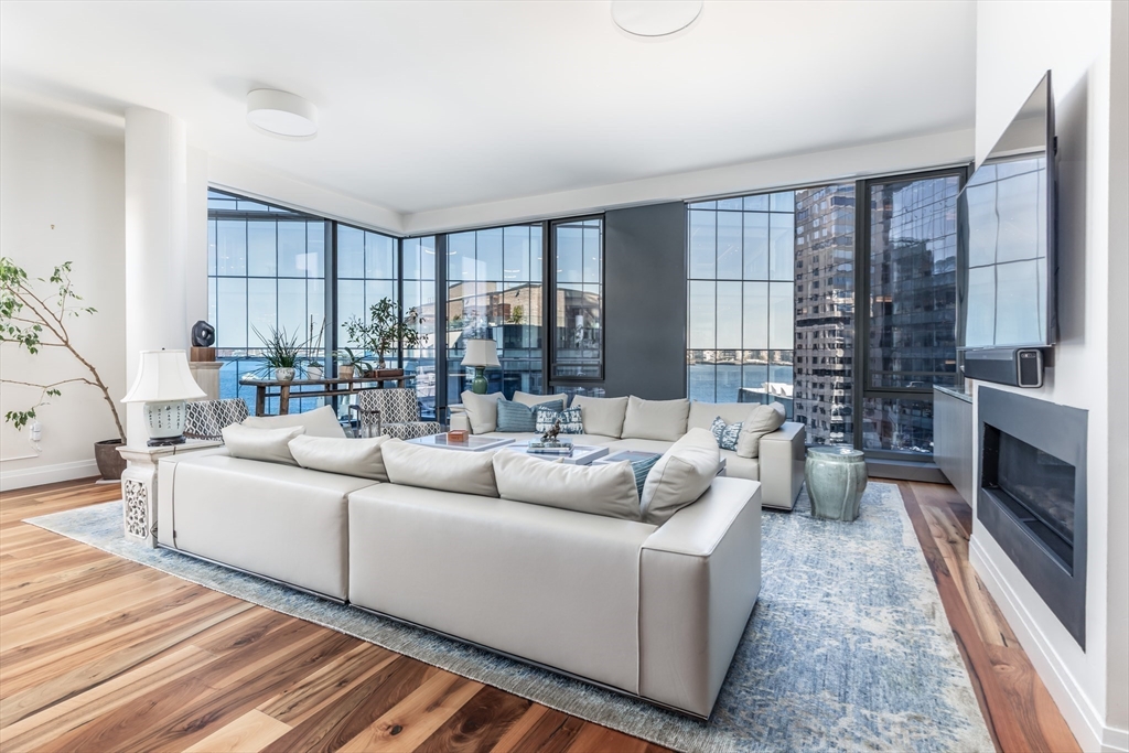 300 Pier 4 Blvd., Unit PHM Boston, MA 02210 - Photo 5 of 34 a living room with furniture large windows and a fireplace