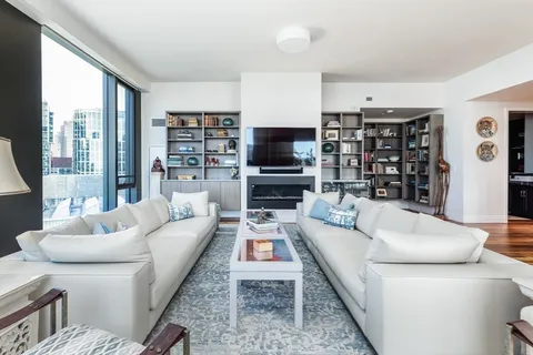 a living room with furniture a flat screen tv and a large window