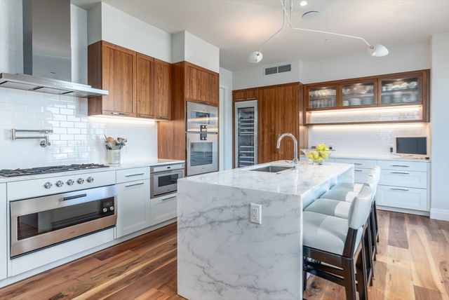 a kitchen with stainless steel appliances kitchen island granite countertop a stove and a sink