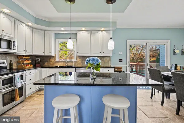 a kitchen with stainless steel appliances granite countertop a kitchen island a table and chairs in it