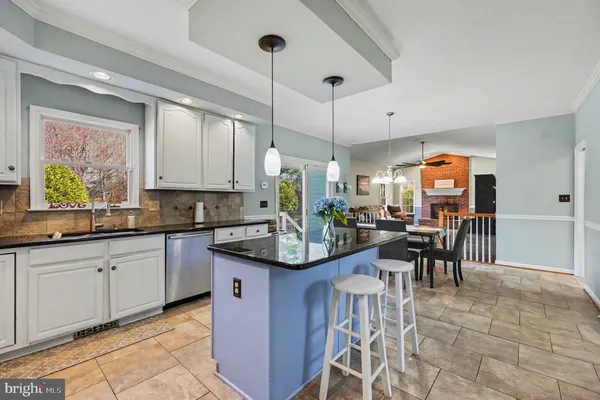 a kitchen with granite countertop a sink a stove and chairs