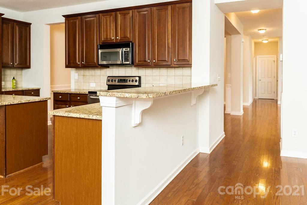 1032 Spanish Moss Road Indian Trail, NC 28079 - Photo 6 of 37 a kitchen with granite countertop wooden cabinets and a stove top oven