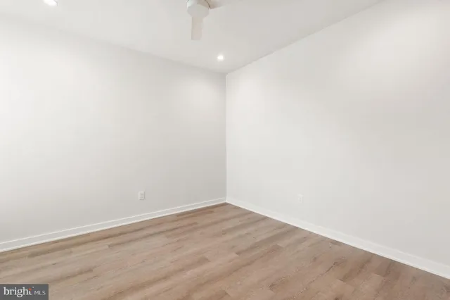 an empty room with wooden floor closet and windows
