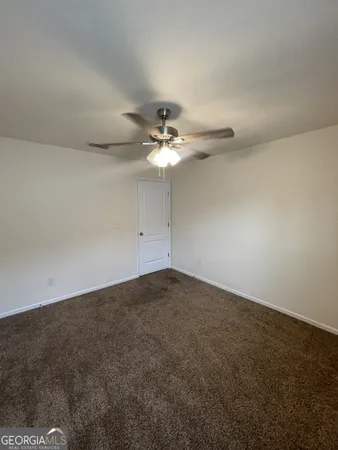 an empty room with a chandelier fan and windows