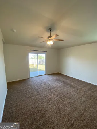 an empty room with a chandelier fan and windows