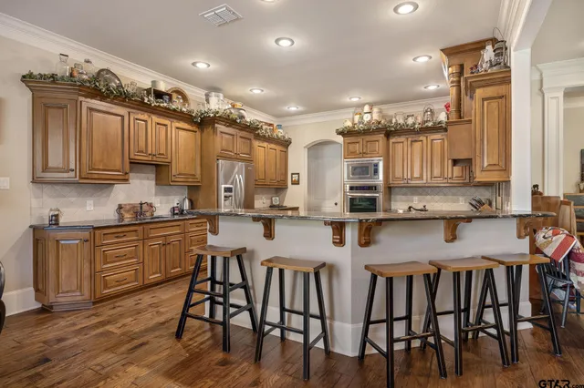 a kitchen with stainless steel appliances granite countertop a kitchen island a stove a cabinets a sink and a chairs