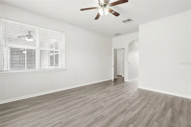 a view of an empty room with wooden floor and a window