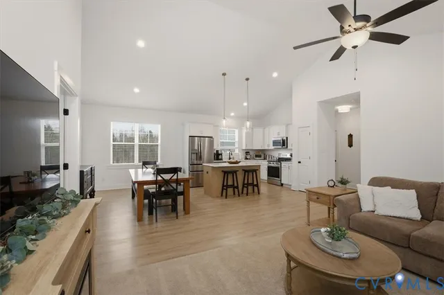 a kitchen with stainless steel appliances granite countertop a stove a refrigerator a kitchen island a dining table and chairs with wooden floor