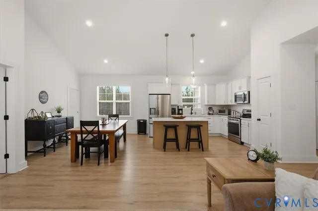 a kitchen with stainless steel appliances granite countertop a sink a stove a refrigerator cabinets and living room view