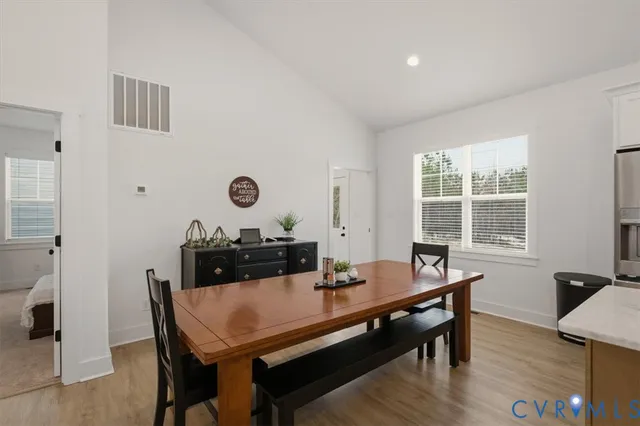 a kitchen with stainless steel appliances granite countertop a refrigerator a sink dishwasher a stove and white cabinets with wooden floor