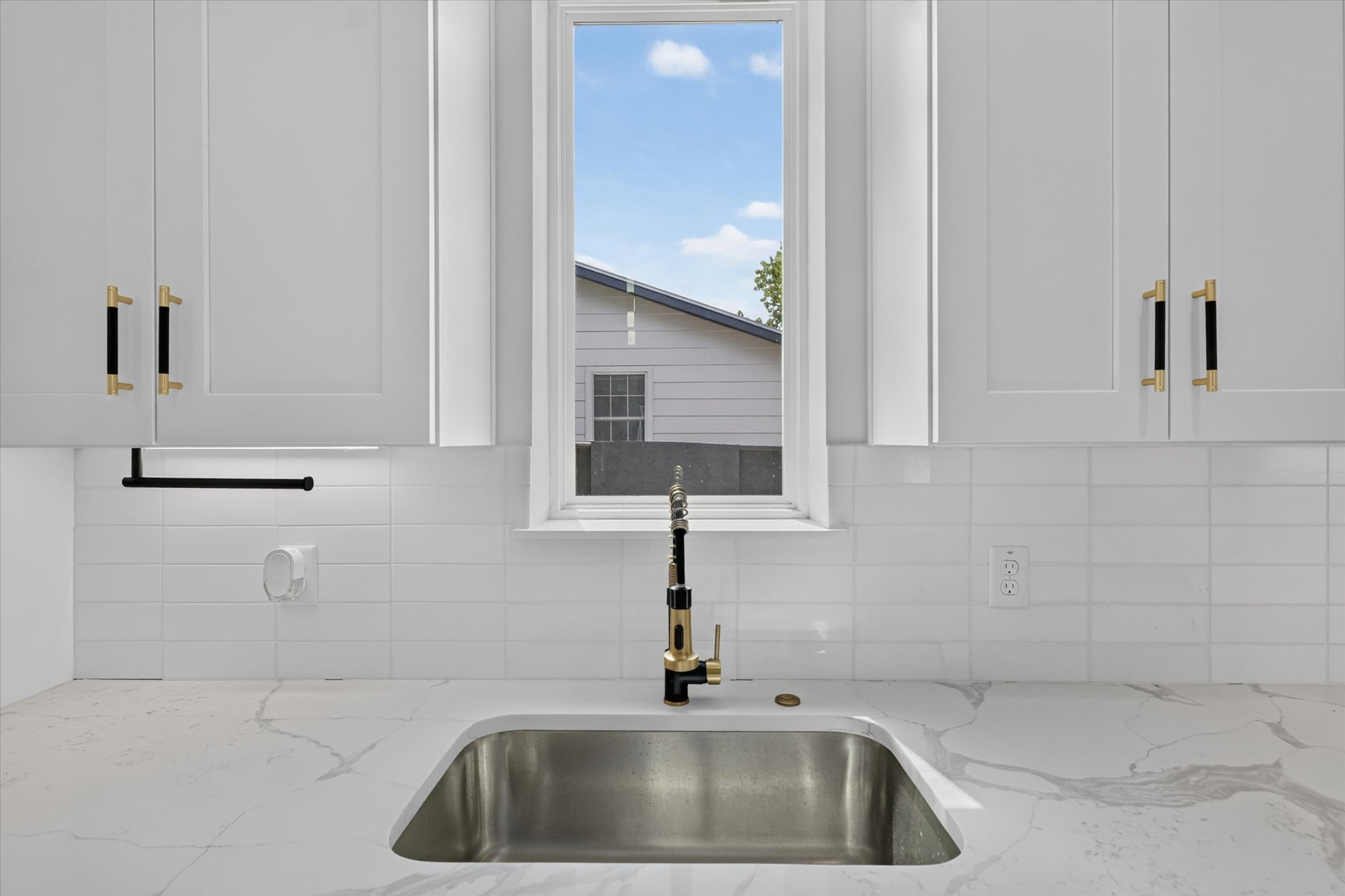 5305 Ledesma Road, Unit 1 Austin, TX 78721 - Photo 15 of 37 Shaker cabinets flank a central window above an undermount sink and stone countertop.