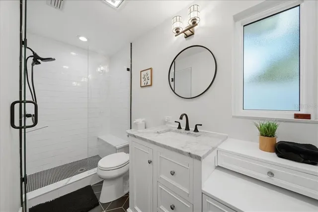a bathroom with a granite countertop sink a toilet and a mirror