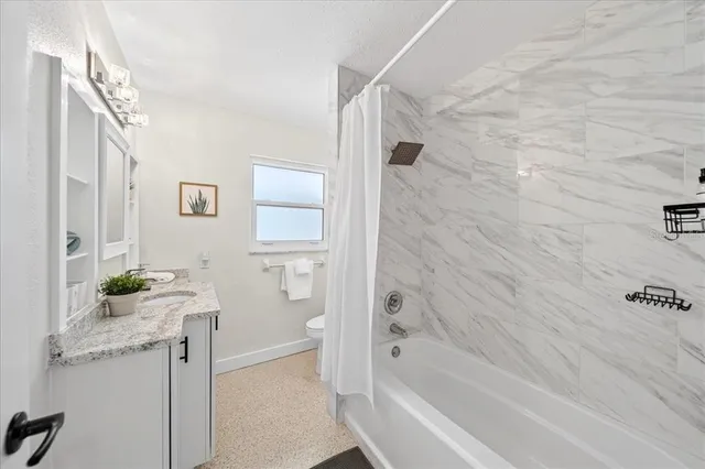 a bathroom with a granite countertop sink a toilet and shower