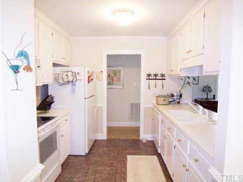 9317 Dawnshire Road Raleigh, NC 27615 - Photo 2 of 9 Open to the LR is the galley-style KIT through an open eat-at b'fast bar. KIT has white cabinets & ctrs, ceramic tile backsplash, stone-look vinyl flr, crown & chair rail molding, smooth-top range, microwave, dishwasher & disposal.