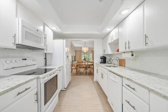 a kitchen with granite countertop white cabinets and white appliances