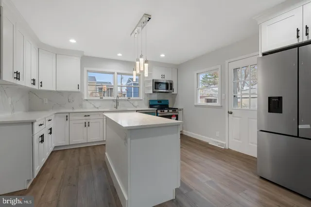 a kitchen with a refrigerator a sink and wooden floor