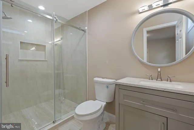 a bathroom with a toilet sink vanity granite and shower