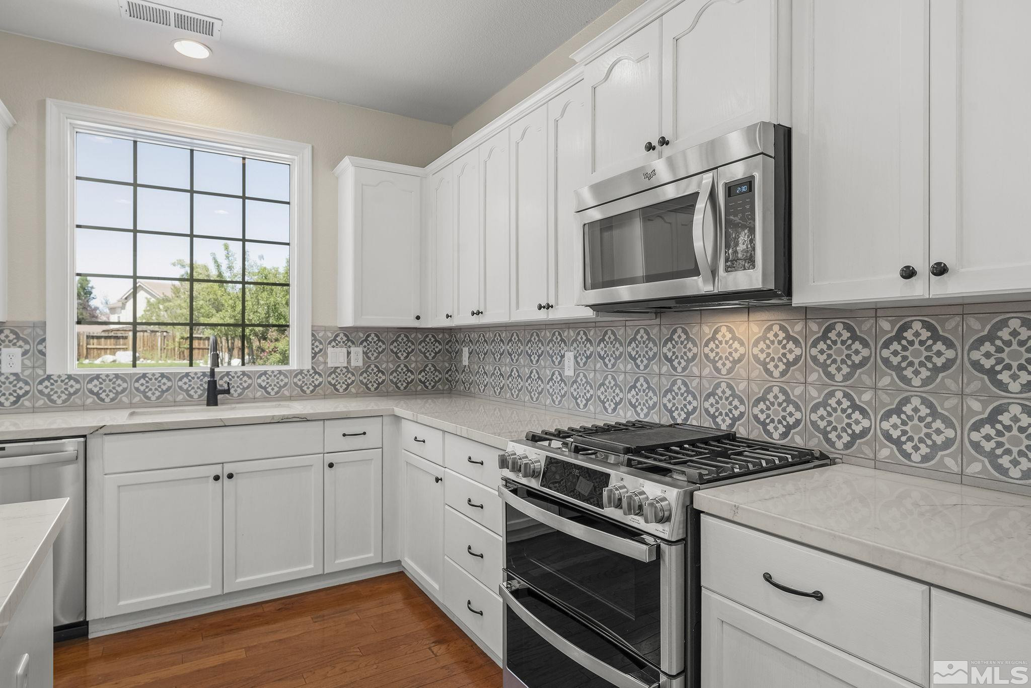 1755 Cavern Drive Reno, NV 89521 - Photo 16 of 25 a kitchen with granite countertop white cabinets stainless steel appliances and a window