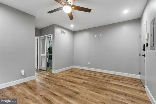 an empty room with a chandelier fan and windows