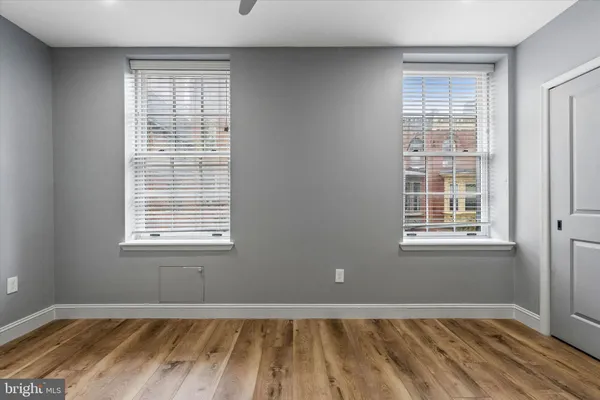 a view of empty room with wooden floor and fan