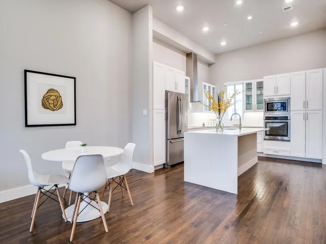 a kitchen with stainless steel appliances a dining table chairs and wooden floor