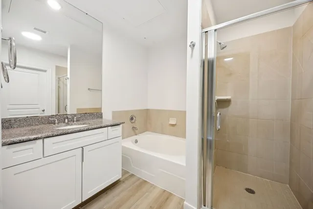 a bathroom with a granite countertop sink a mirror a bathtub and a shower
