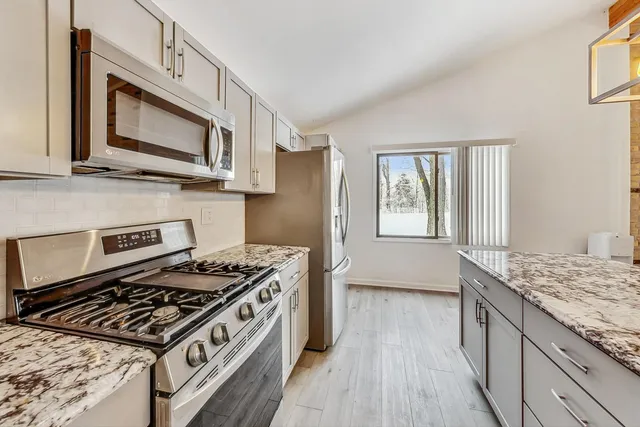 a kitchen with stainless steel appliances granite countertop a stove and a microwave