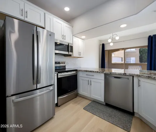 a kitchen with granite countertop a refrigerator stove and sink