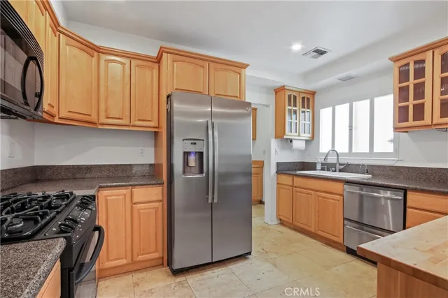 a kitchen with stainless steel appliances granite countertop a refrigerator a sink and a stove