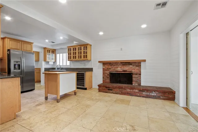a view of kitchen with stainless steel appliances kitchen island wooden cabinets and fireplace