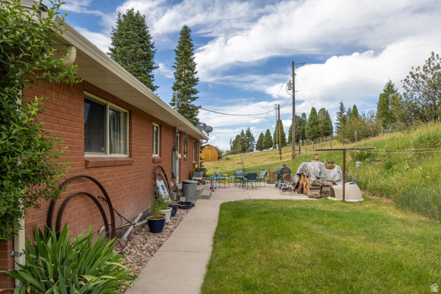 322 Bailey Creek Road Soda Springs, ID 83276 - Photo 26 of 32 Red brick exterior featuring white window frames, a concrete walkway, and an expansive lawn
