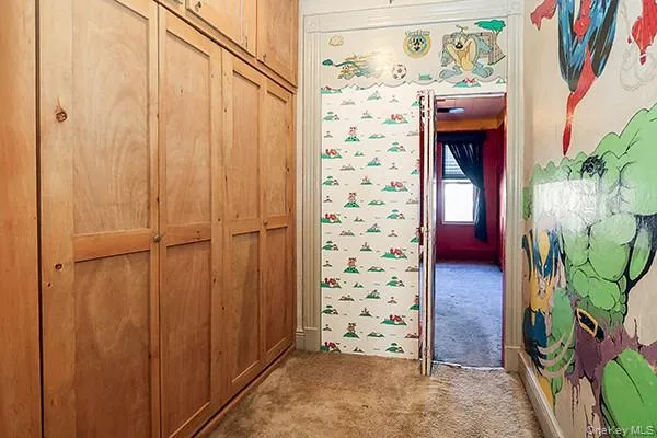 a view of an empty room with window and chandelier fan