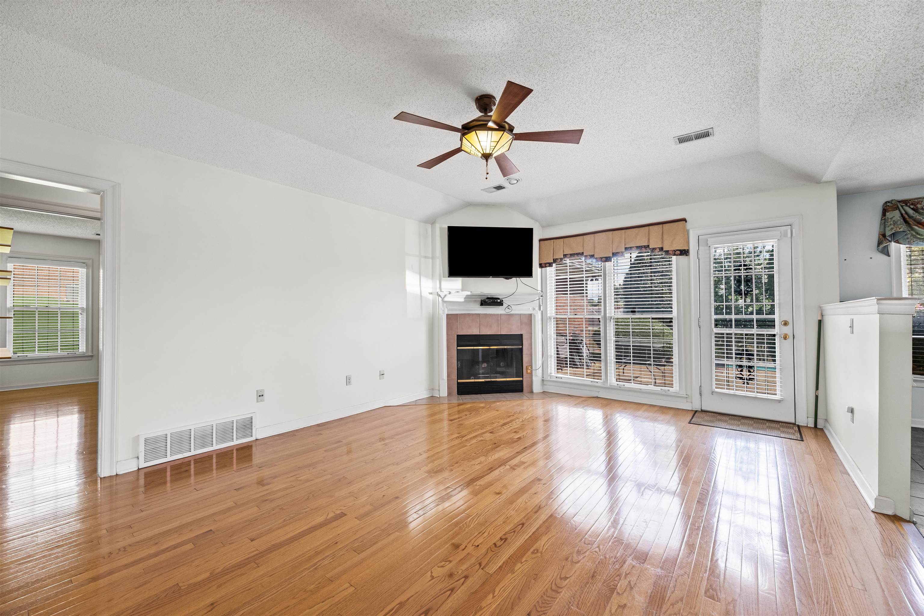 8645 Bazemore Road Memphis, TN 38018 - Photo 14 of 28 Unfurnished living room featuring a fireplace, plenty of natural light, lofted ceiling, ceiling fan, and a textured ceiling