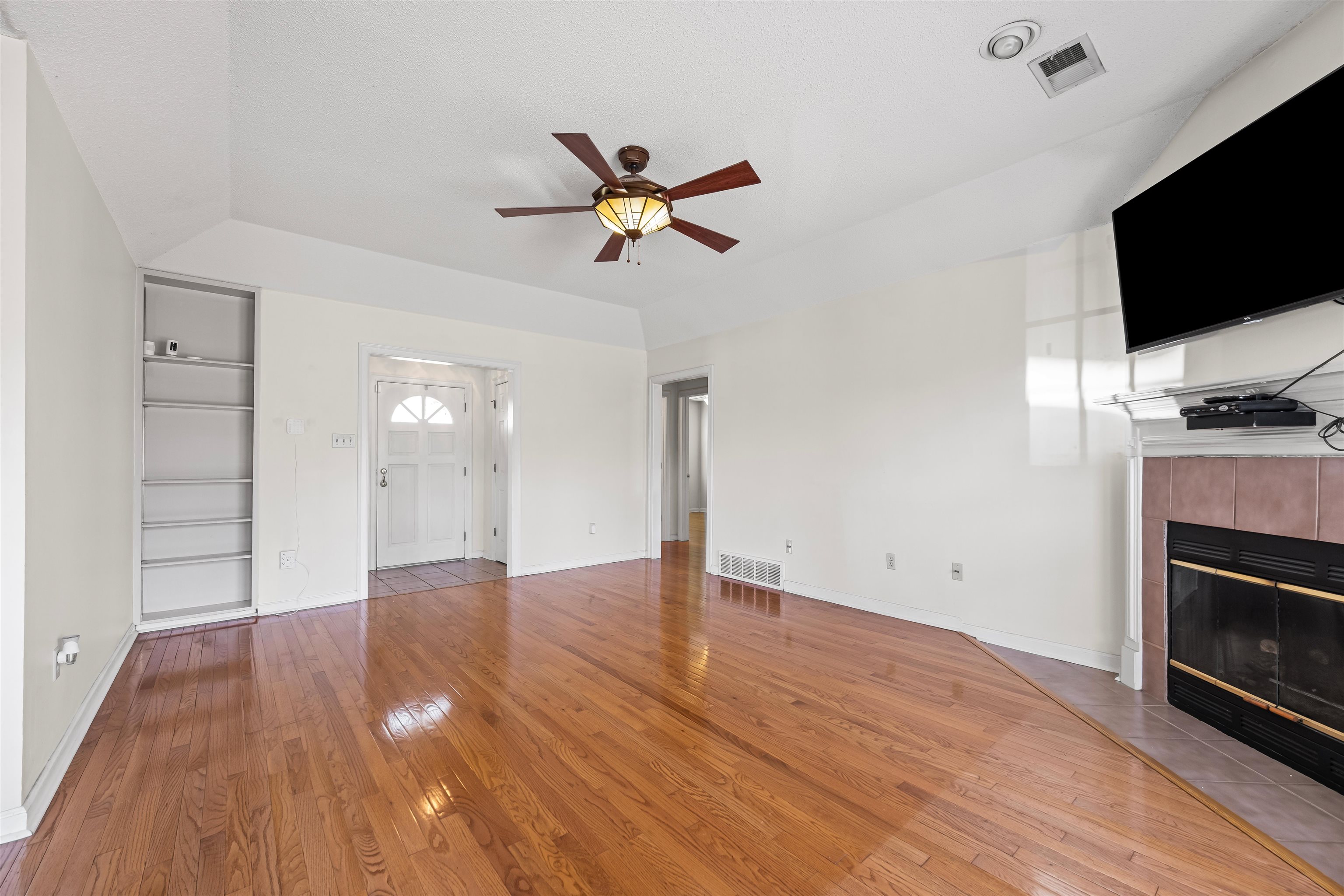 8645 Bazemore Road Memphis, TN 38018 - Photo 15 of 28 Unfurnished living room with a ceiling fan, light wood-type flooring, and a tiled fireplace