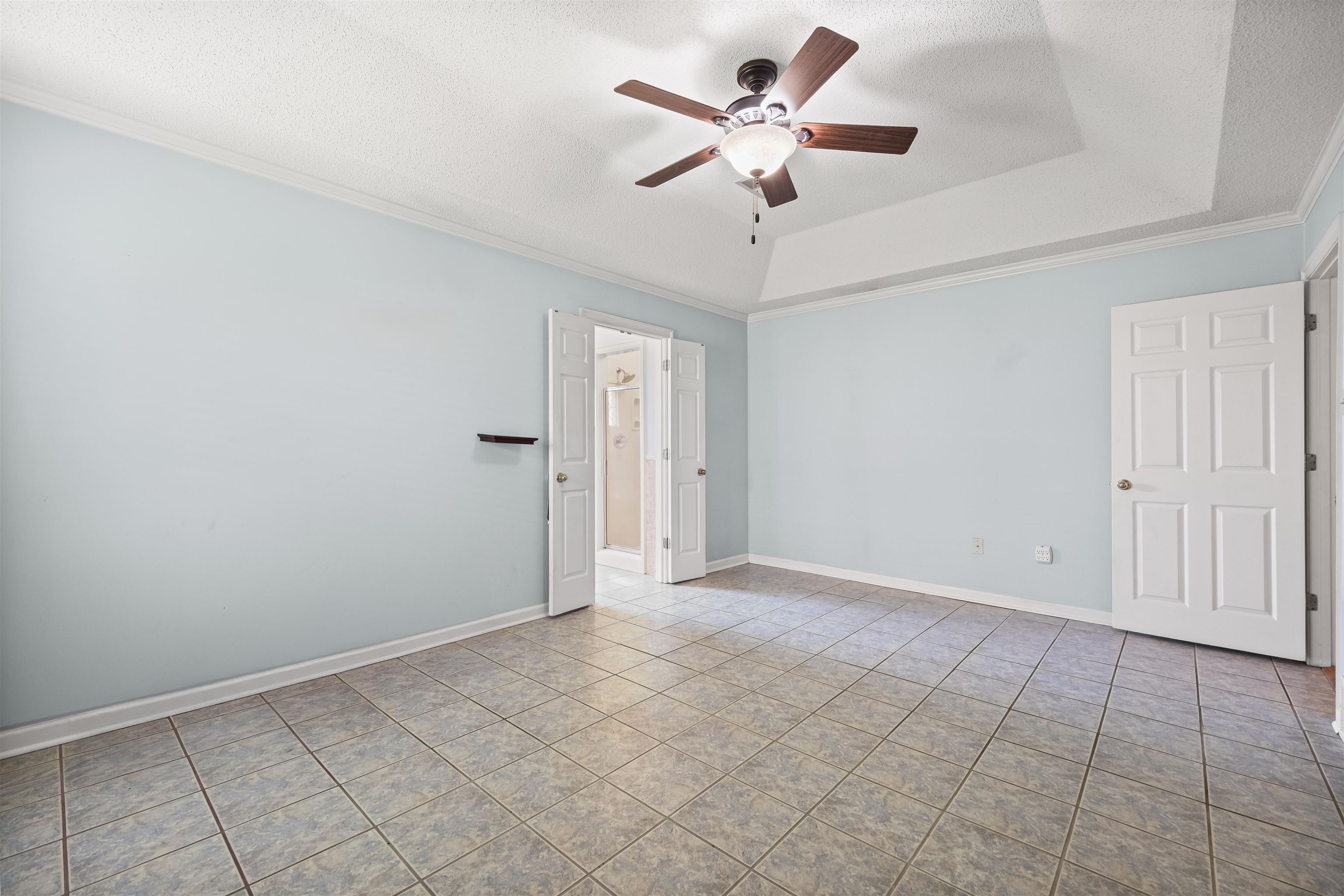 8645 Bazemore Road Memphis, TN 38018 - Photo 16 of 28 Empty room featuring ceiling fan, tile patterned flooring, ornamental molding, a tray ceiling, and a textured ceiling