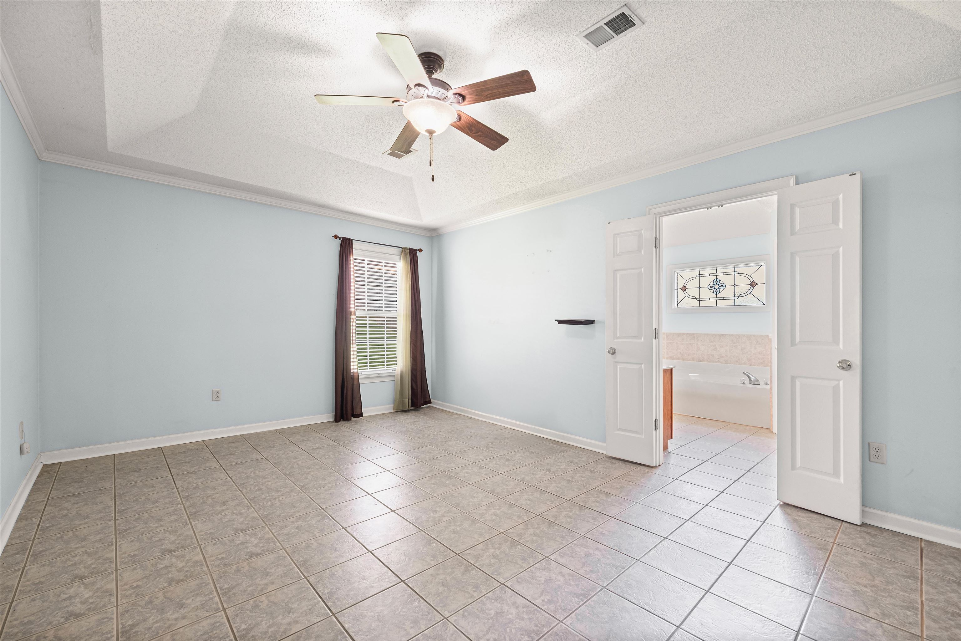 8645 Bazemore Road Memphis, TN 38018 - Photo 17 of 28 Spare room featuring ceiling fan, crown molding, light tile patterned floors, a textured ceiling, and a tray ceiling