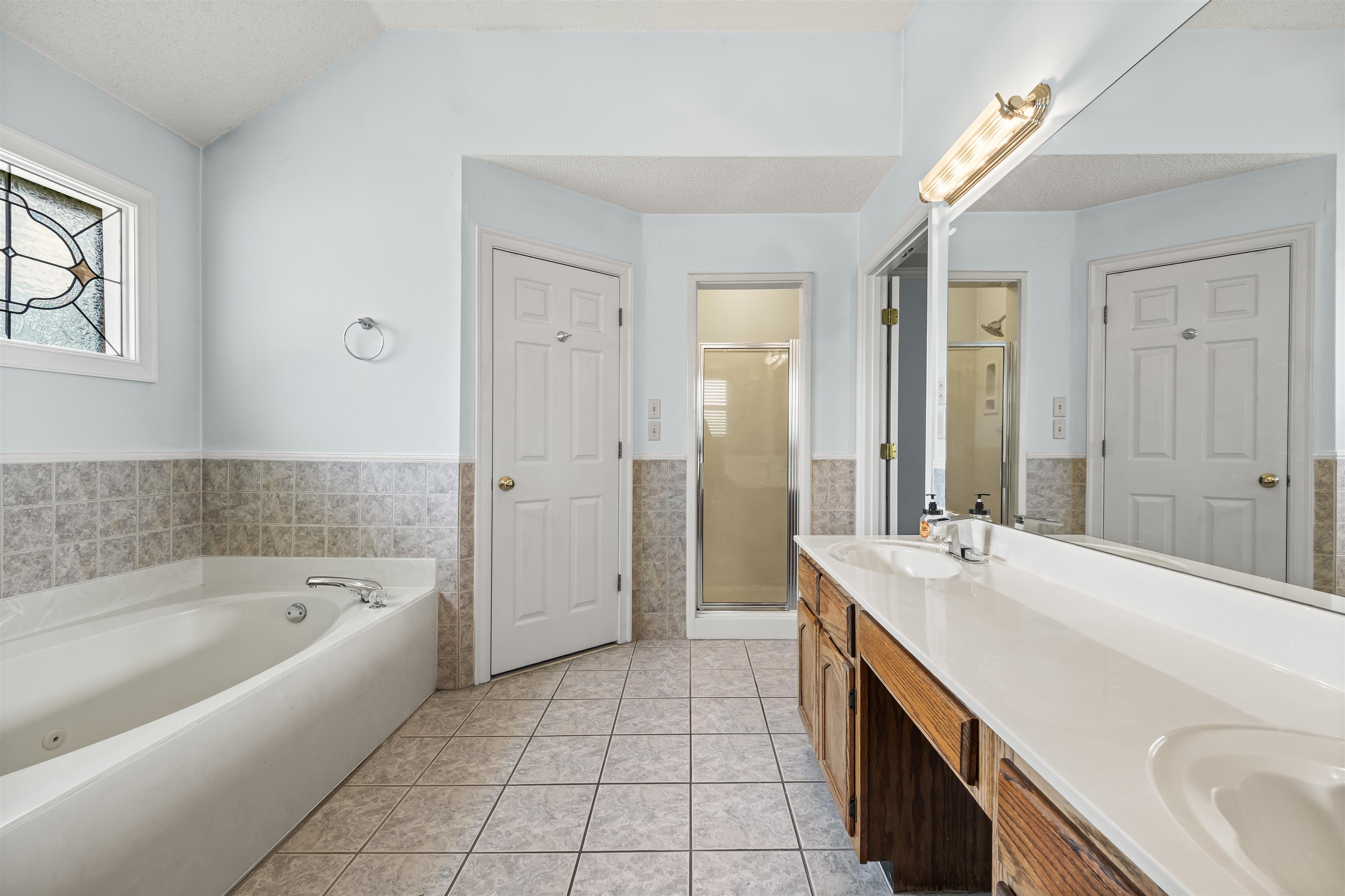 8645 Bazemore Road Memphis, TN 38018 - Photo 19 of 28 Full bathroom with tile walls, a shower stall, a whirlpool tub, double vanity, and a wainscoted wall