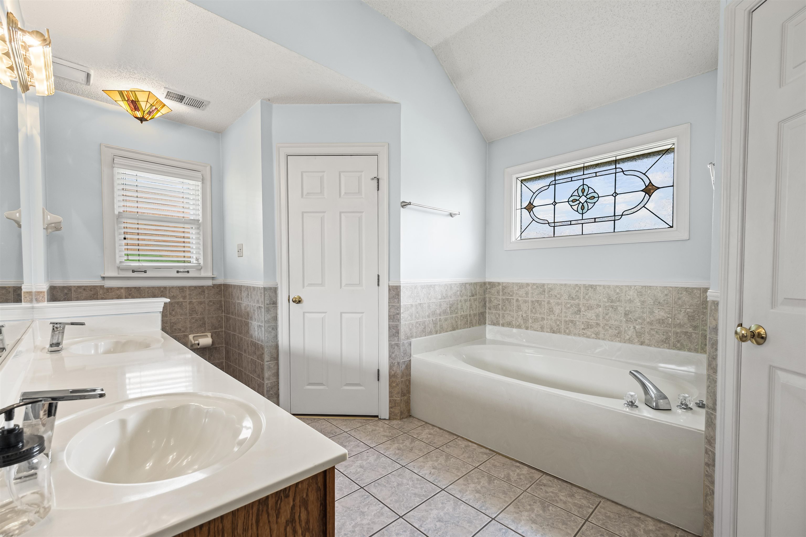 8645 Bazemore Road Memphis, TN 38018 - Photo 20 of 28 Bathroom with tile walls, tile patterned floors, double vanity, a bath, and lofted ceiling